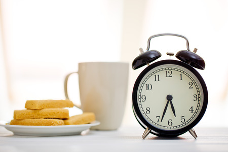 alarm clock and breakfast on white tableの写真素材