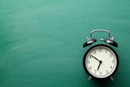 alarm clock on green chalkboardの写真素材