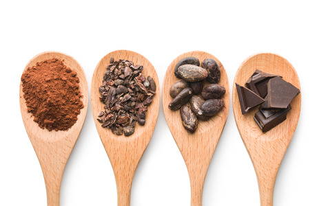 cocoa and dark chocolate in wooden spoons on white background