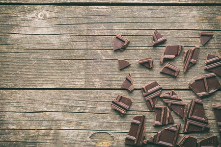 broken dark chocolate on old wooden background