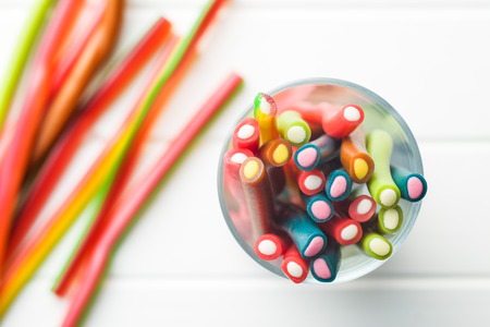 Sweet gummy sticks with different flavor. Top view of tasty candy in glass cup.