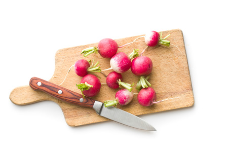 Fresh radishes on old cutting board. Red radishes isolated on white background. Top view.の写真素材