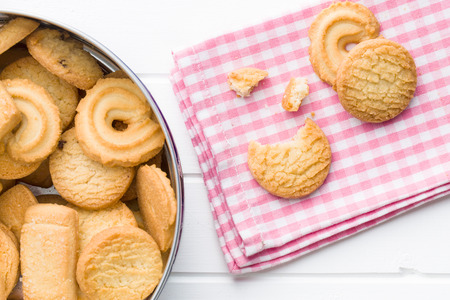 Sweet butter biscuits. Top view of cookies in can and on checkered napkin.