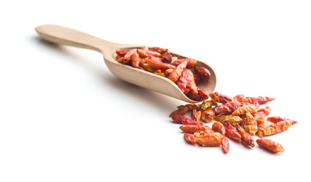 Dried mini chili peppers in wooden scoop. Isolated on white background.の写真素材