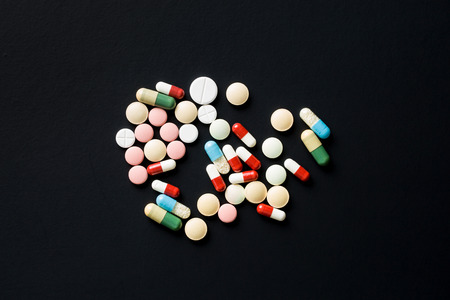The different pills on black table. Top view.