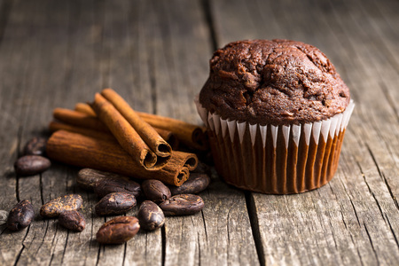 The tasty chocolate muffin and cocoa beans on old wooden table.の写真素材