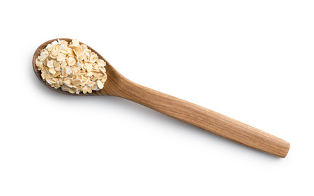 Dry rolled oatmeal in wooden spoon. Isolated on white.の写真素材