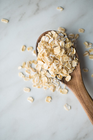 Dry rolled oatmeal in wooden spoon. Top view.の写真素材