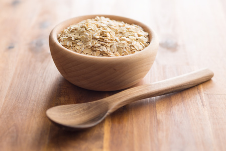 Dry rolled oatmeal in wooden bowl.の写真素材