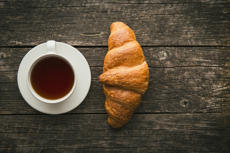 Tasty buttery croissant and cup of tea. Top view.の写真素材
