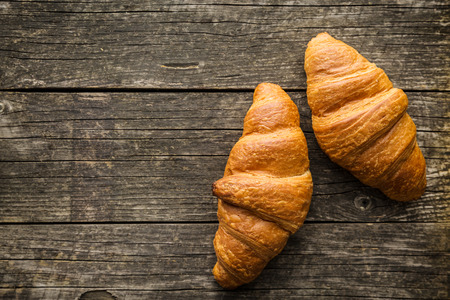 Tasty buttery croissants on old wooden table.の写真素材
