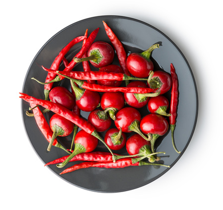 Red chili peppers on plate isolated on white background.の写真素材