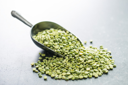 Green split peas in metal scoop on old kitchen table.の写真素材
