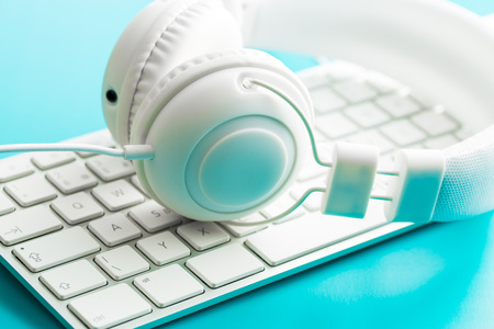 White headphones and computer keyboard on blue background.の写真素材