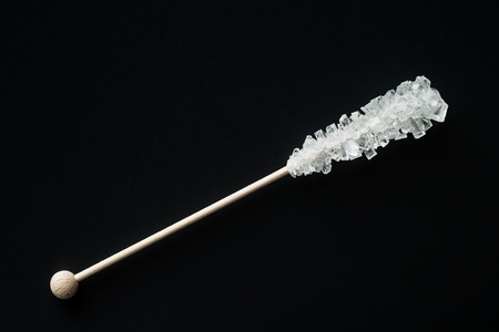 Crystallized sugar on wooden stick on black background. Top view.の写真素材