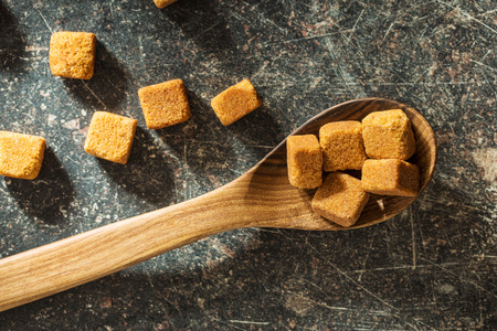 Brown sugar cubes in wooden spoon. Top view.の写真素材