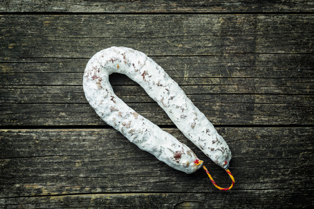 Tasty salami with white mold on old wooden table.の写真素材