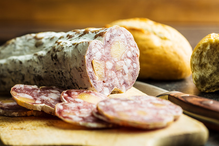Tasty sliced salami with white mold on cutting board.