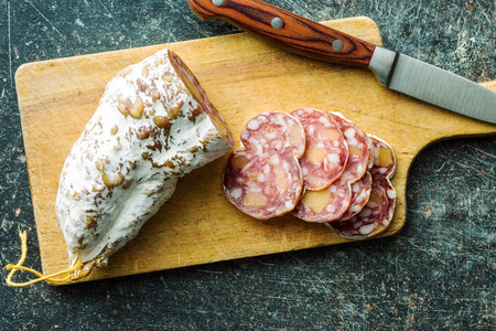 Tasty sliced salami with white mold on cutting board. Top view.
