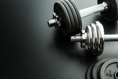 The metal dumbbell and weights on black background.