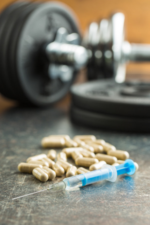 Doping in sport. Syringe and dumbbell.の写真素材