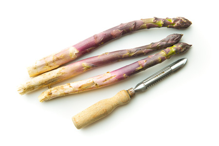 Fresh purple asparagus with peeler isolated on white backgrund.の写真素材