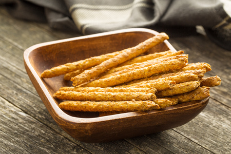Salty pretzel sticks in wooden bowl.