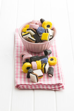 Mixed liquorice candies in bowl on kitchen table.のeditorial素材