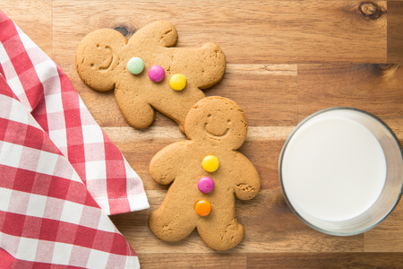 Sweet gingerbread men and glass of milk. Xmas gingerbread on wooden table.の写真素材