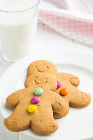 Sweet gingerbread men and glass of milk. Xmas gingerbread on white table.