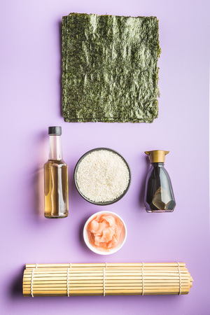 The sushi ingredients on purple table. Rice, ginger, soy sauce, vinegar and nori sheets.の写真素材