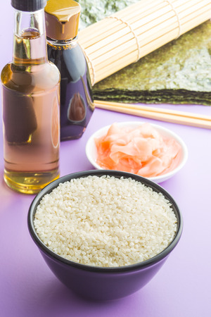 The sushi ingredients on purple table. Rice, ginger, soy sauce, vinegar and nori sheets.の写真素材