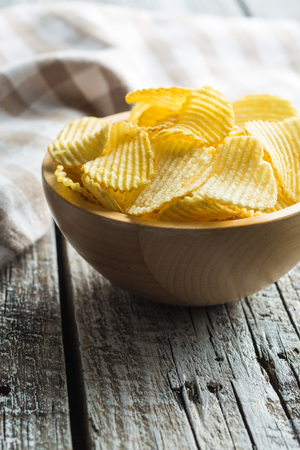 Crispy potato chips in wooden bowl. Salted potato chips.の写真素材