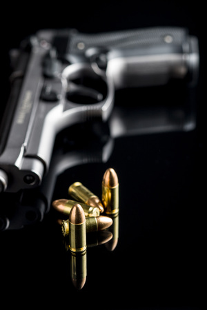 9mm pistol bullets and handgun on black table.の写真素材