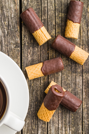 Sweet dessert. Biscuits rolls with chocolate icing on old wooden table.の写真素材