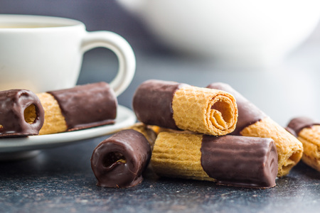 Sweet dessert. Biscuits rolls with chocolate icing on old kitchen table.の写真素材