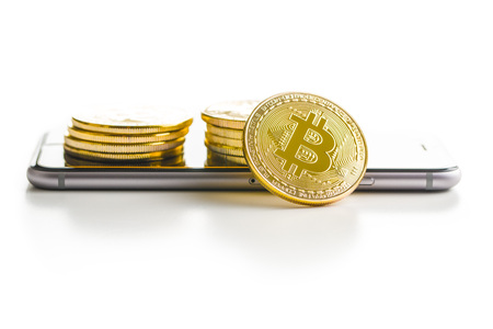 Bitcoin lies on a smartphone isolated on white background.