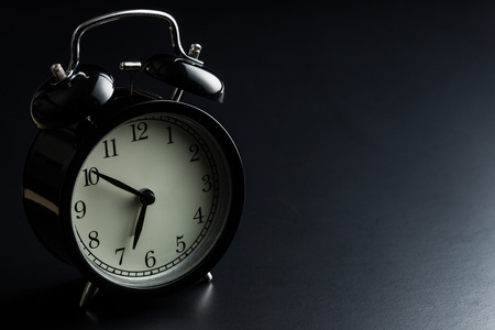 Black alarm clock on black background.