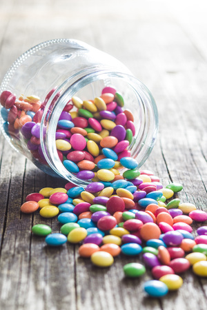 Colorful chocolate candies in jar on old kitchen table.の写真素材