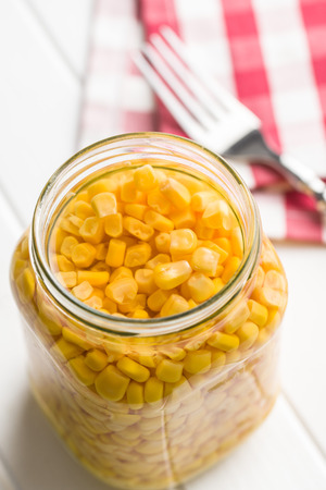 Corn seed in glass jar isolated on white table.の写真素材