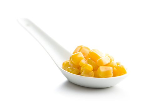 Corn seeds in ceramic spoon isolated on white background.の写真素材