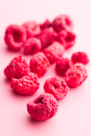 Freeze dried raspberries on pink background.