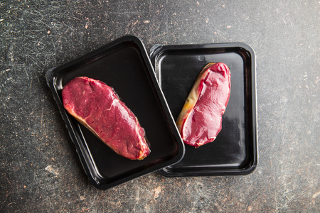 Fresh raw beef meat in foil box on old kitchen table.の写真素材