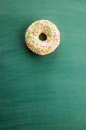 Sweet sprinkled donut on green chalkboard.の写真素材