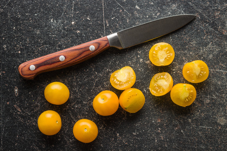 Yellow cherry tomatoes and knife on old kitchen table.の写真素材