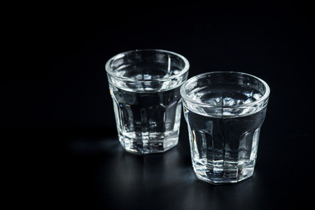 Vodka in shot glass. Transparent alcohol on black table.の写真素材