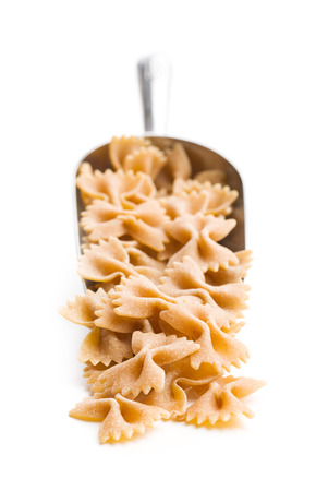 Wholewheat farfalle pasta. Tasty italian pasta in scoop isolated on white background.の写真素材
