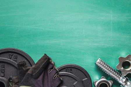 Dumbbell and fitness gloves on green chalkboard.の写真素材