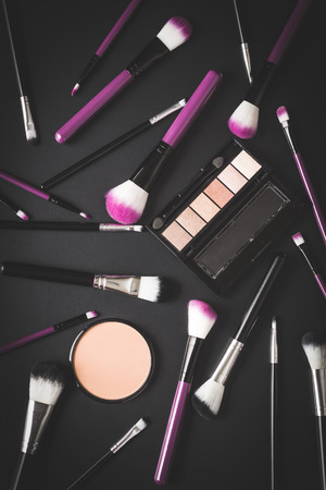 The makeup products. Brush and eyeshadow powder on black table.の写真素材