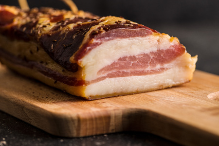 Block of tasty smoked bacon on cutting board.の写真素材